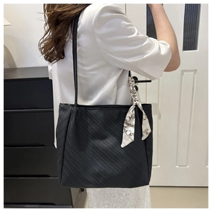 Detail of black tote bag with textured surface and decorative chain print silk scarf
