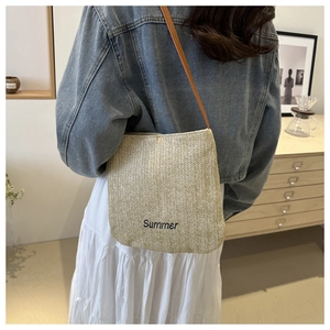 Detail of straw tote bag featuring Summer embroidery and brown leather shoulder strap