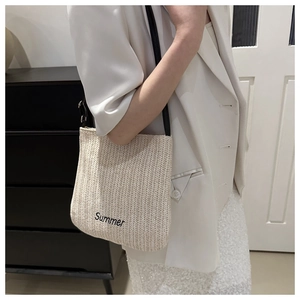 Detail of Summer letter embroidery on woven straw tote bag with black shoulder strap