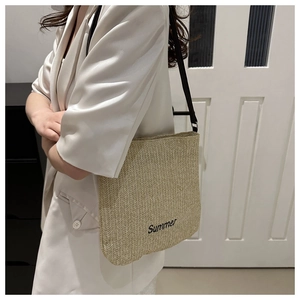 Side view of large straw tote bag with black Summer embroidery worn over the shoulder