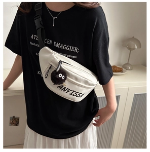 Close-up of white nylon crossbody bag with black letter print and plush soot sprite charm