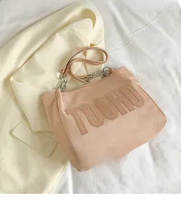 Detail of pink tote bag with TOOHO embroidery, leather strap, and decorative metal chain