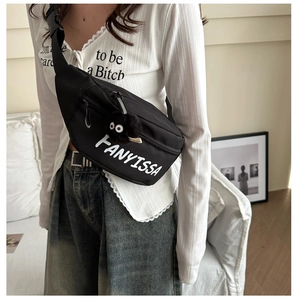 Detail van zwarte crossbody tas met witte FANYISSA print en een schattige hanger