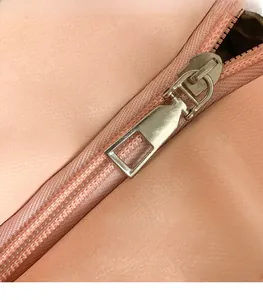 Macro shot of silver metal zipper on pink textured faux leather tote bag detail