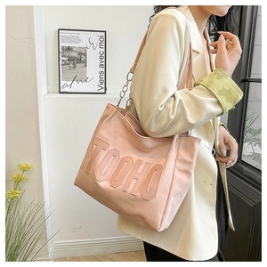 Detail of pink tote bag with embossed letters and chain shoulder strap on model