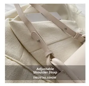 Gros plan de la bandoulière en cuir réglable avec boucle argentée sur un sac crème