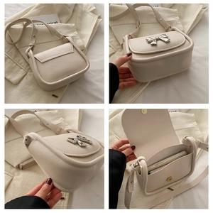Vue détaillée du sac selle blanc crème avec nœud en métal argenté et intérieur compact