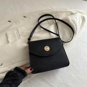 Sac bandoulière noir en demi-lune avec boucle dorée sur un blazer de couleur crème