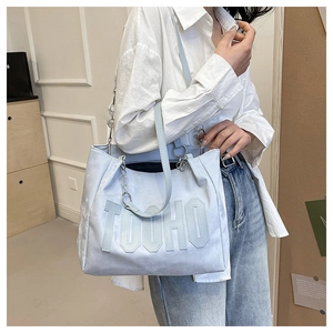 Detail of light blue suede tote bag with TOOHO letter embroidery and chain strap