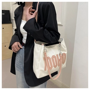 Close-up of large white tote bag with orange DOHO lettering and metal chain strap