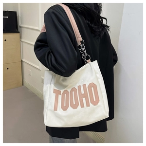 Detail view of white tote bag with pink 3D letters and silver metal chain shoulder strap
