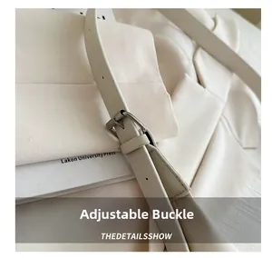 Gros plan de la bandoulière réglable avec boucle argentée sur un sac cabas beige