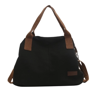 Large black canvas tote bag with brown straps and detachable shoulder strap on white background