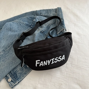 Zwarte crossbodytas met FANYISSA letters op een achtergrond van een denim jasje