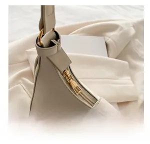 Detail view of the smooth light gold metal zipper on a cream white leather underarm bag