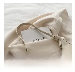 Detailed close-up of a cream-colored leather shoulder bag with a wide comfortable strap