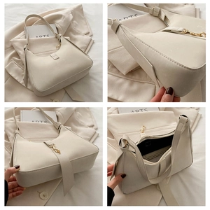 Detail view of cream crescent bag showing stitching, gold clasp, and interior pockets