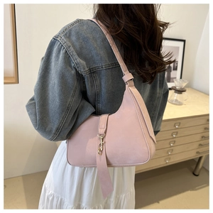 Detail of light pink hobo shoulder bag with gold metal buckle and decorative ribbon