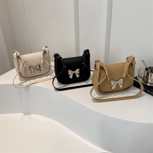 Trois sacs selle minimalistes en crème, noir et fauve avec boucles de nœud en métal