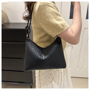 Detail shot of a black woven leather hobo bag with an elegant shoulder strap knot