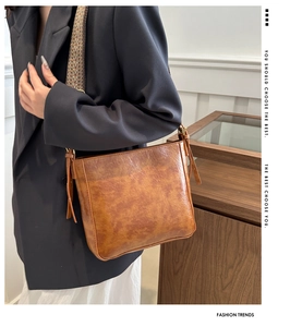 Detail of vintage brown leather bucket bag with geometric patterned wide shoulder strap