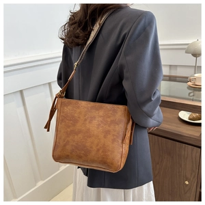 Detail of vintage brown textured leather tote with patterned wide strap on a model