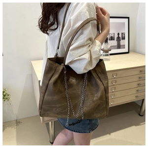 Detail view of large brown suede tote bag with silver chain and TIDALWAVES logo