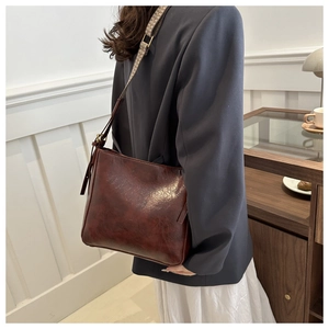 Detail of vintage reddish-brown shoulder bag with stylish jacquard wide strap and glossy finish