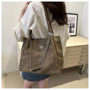 Detail of vintage brown tote bag featuring silver chains and white logo branding