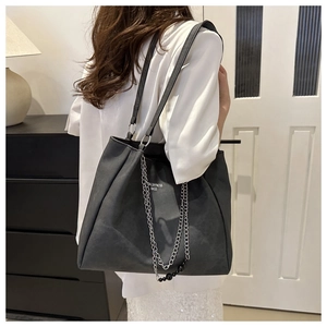 Detail of black large capacity tote bag with silver chain and bead charm on model