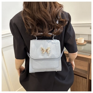 Detail of light blue Y2K backpack with liquid metal butterfly buckle on faux leather