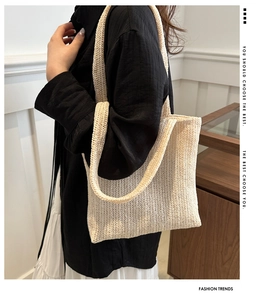 Detailed close-up of the beige woven tote bag showing its intricate knit texture and strap