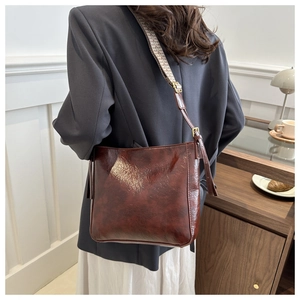 Detail of dark brown faux leather bag with wide vintage patterned shoulder strap and gold hardware