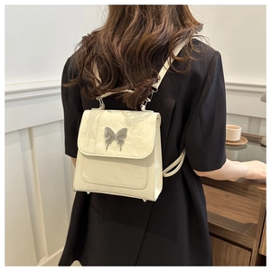 Detail of cream-colored bucket bag featuring silver butterfly buckle and crinkled texture