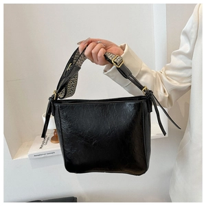 Detail of black leather bucket bag with stylish black and white herringbone wide strap