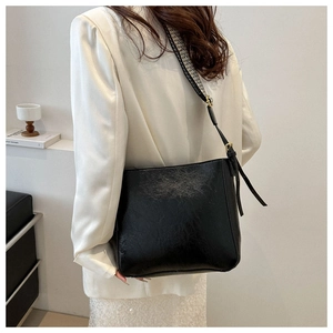 Detail of vintage black cracked texture bucket bag with geometric woven shoulder strap