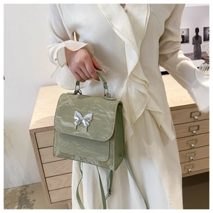 Detail of mint green crinkled patent leather bucket bag with silver butterfly buckle