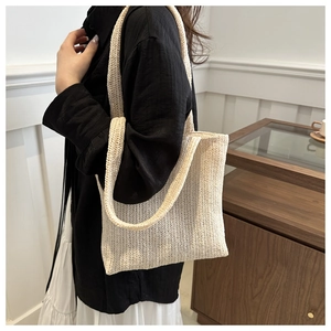 Detail of cream woven tote bag texture and long shoulder strap in minimalist home setting