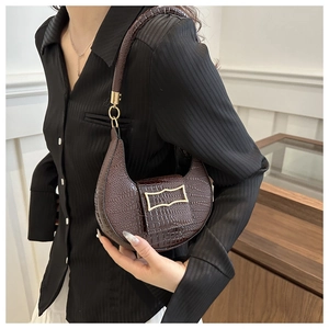 Detail shot of a dark brown crocodile pattern hobo bag with a gold buckle clasp