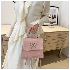 Detail of light pink backpack with pleated texture and silver butterfly metal buckle