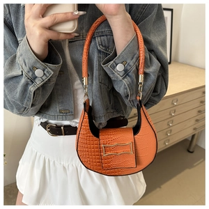 Detail of orange crescent handbag with crocodile texture shown in casual outfit