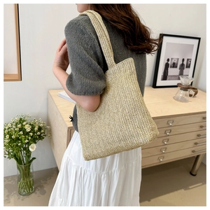 Detailed view of natural beige woven tote bag with V-shaped texture on wide shoulder strap