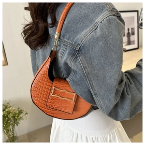 Detail of orange crocodile pattern half-moon shoulder bag with gold metal buckle