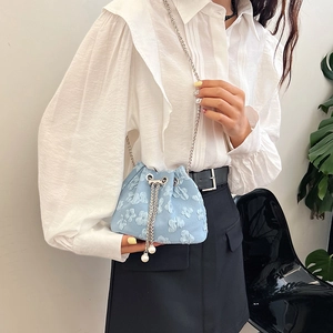 Sac seau bleu clair à fleurs avec chaîne argentée et cordon perlé sur modèle