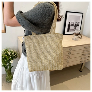 Detailed side view of a large woven straw tote bag with long double shoulder straps