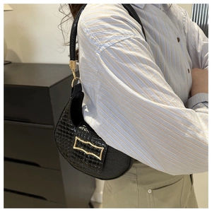 Detailed view of black crocodile-textured hobo bag with elegant gold metal hardware