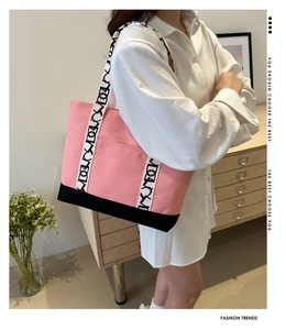 Détail du cabas en toile avec panneau rose contrasté et bandoulière tissée logotypée