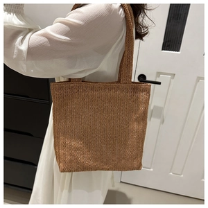 Close-up of brown woven tote bag with detailed herringbone pattern and wide straps