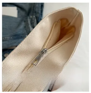 Vue détaillée de la fermeture à glissière en métal lisse de ce sac cabas en toile crème