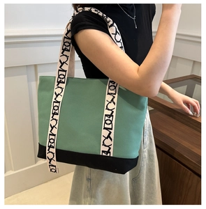 Détail du sac cabas en toile montrant le design bicolore et la sangle logo